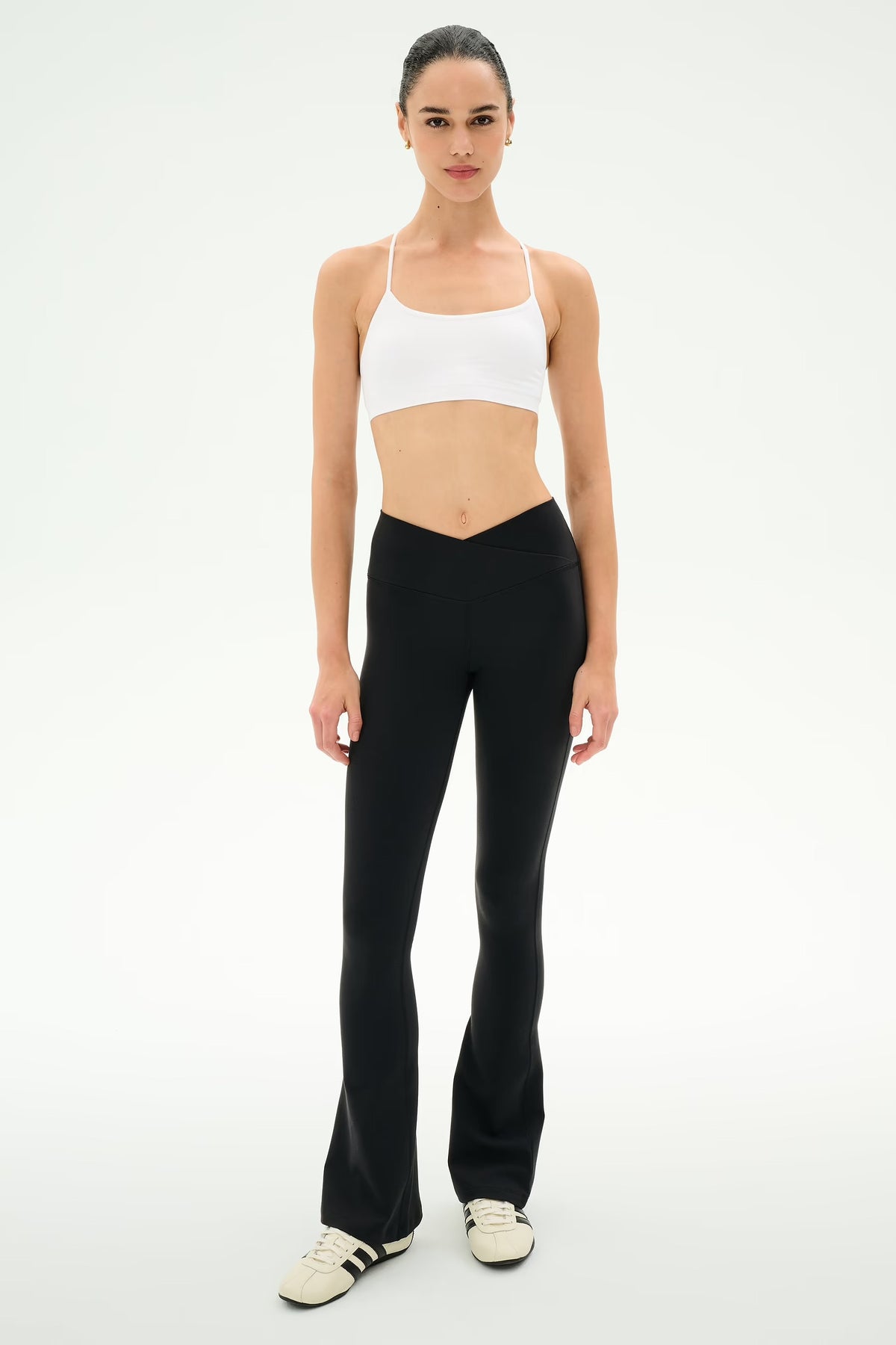woman modeling crossover flare leggings and a white sports bra