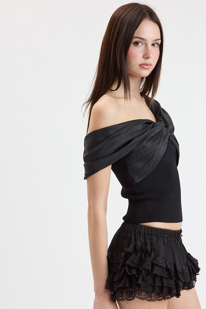 Woman wearing a black off-shoulder top with a ruffled skirt on a white background