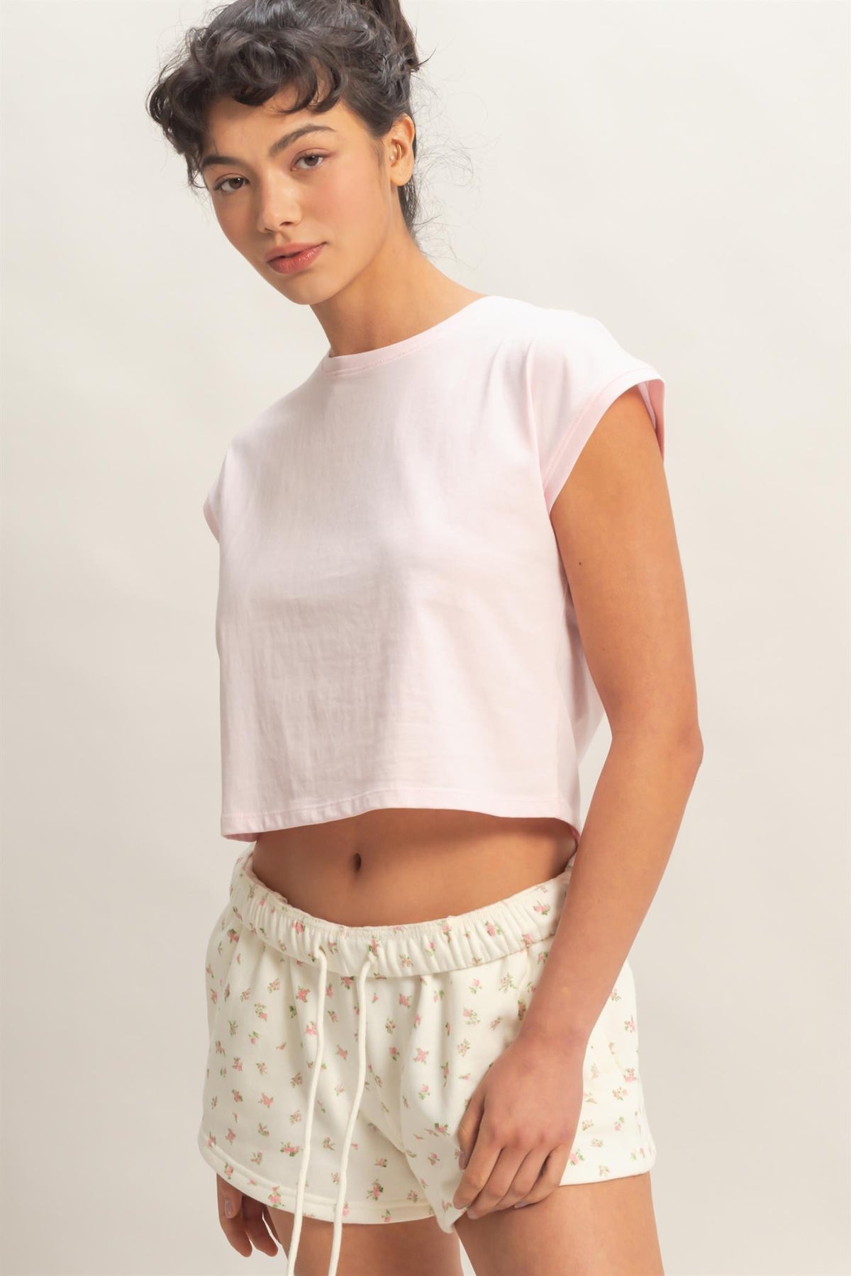 Woman wearing a pink crop top against a plain background