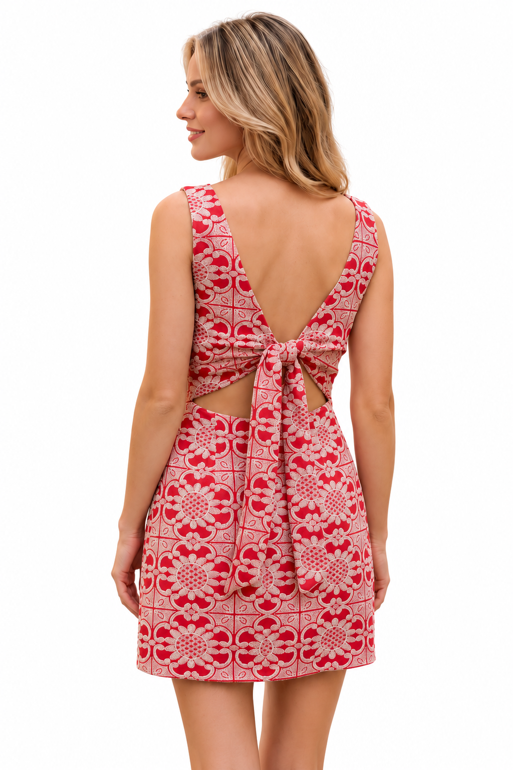 A woman shown from the back wearing a sleeveless red and white patterned dress with a tie-back detail and side cutouts, photographed against a plain white background.