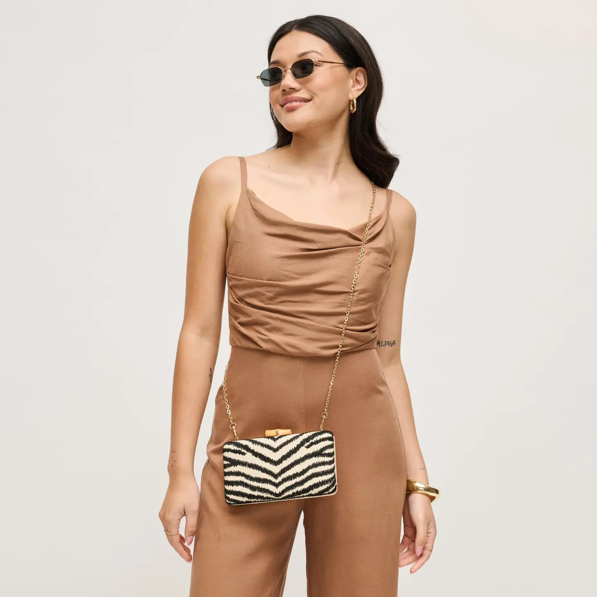 woman wearing sunglasses holding a zebra rectangle clutch 