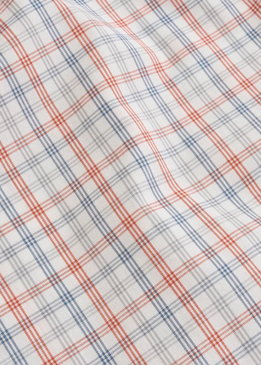 A close-up of a plaid fabric pattern with a white base, featuring intersecting red and blue diagonal lines.