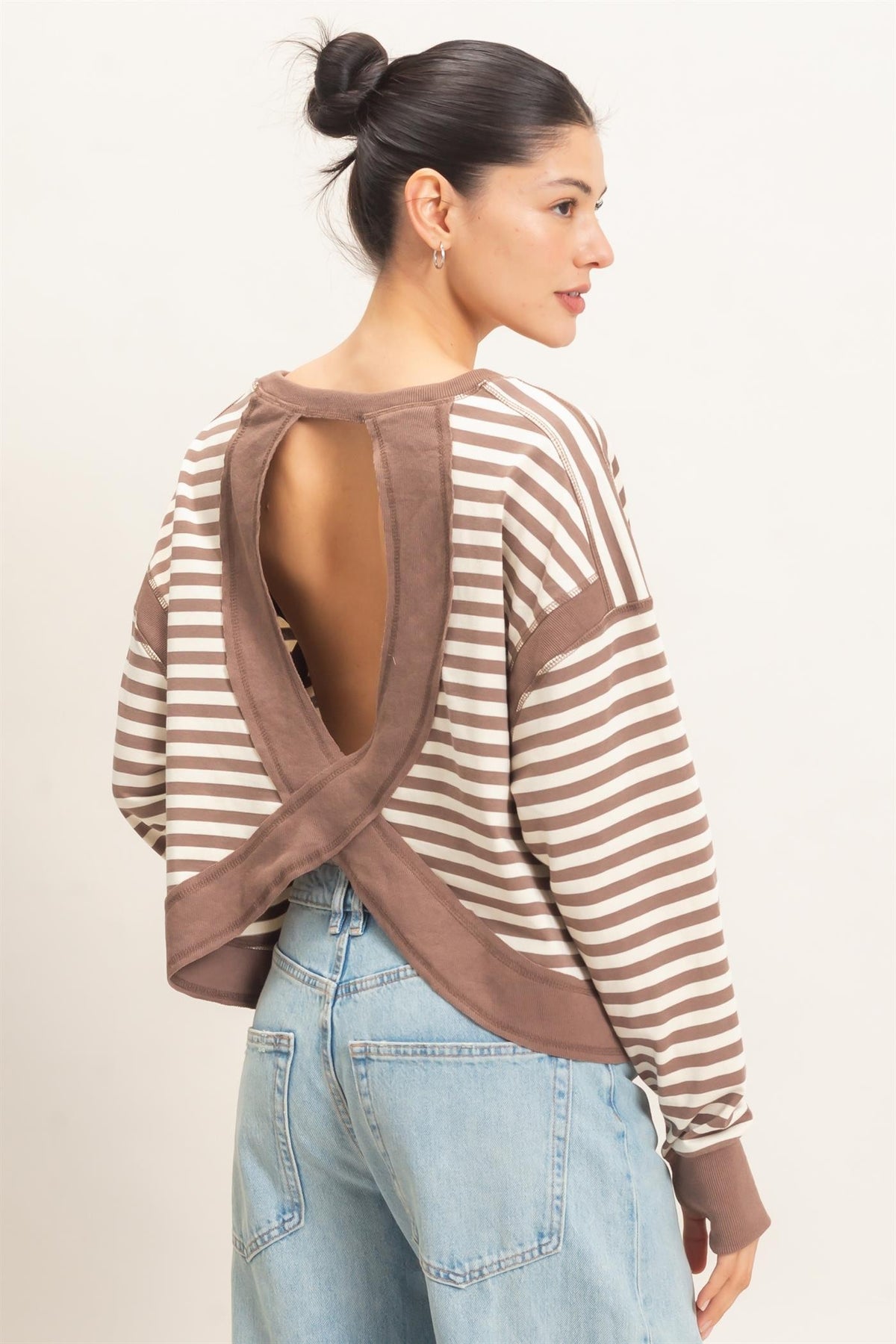 woman standing with her back to the camera modeling a taupe and white striped top with a round open back 