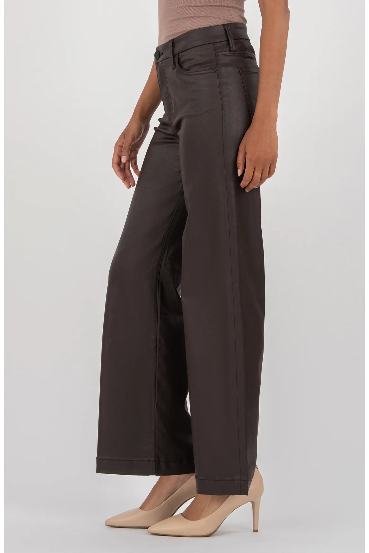 A model wearing dark brown wide-leg trousers paired with beige high heels and a matching beige top, shown from the waist down against a light gray studio background.