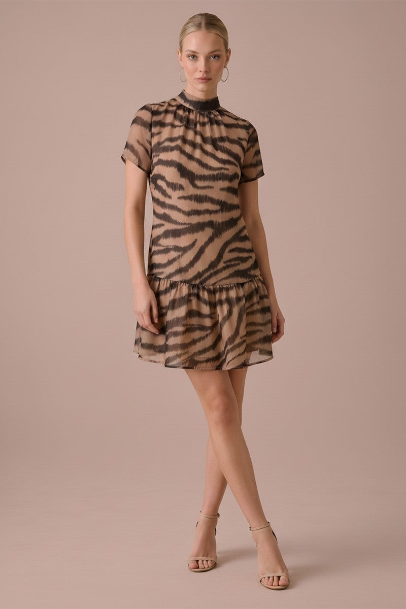 A woman modeling a short-sleeve mini dress with a brown and beige tiger stripe pattern against a solid dusty pink studio background.