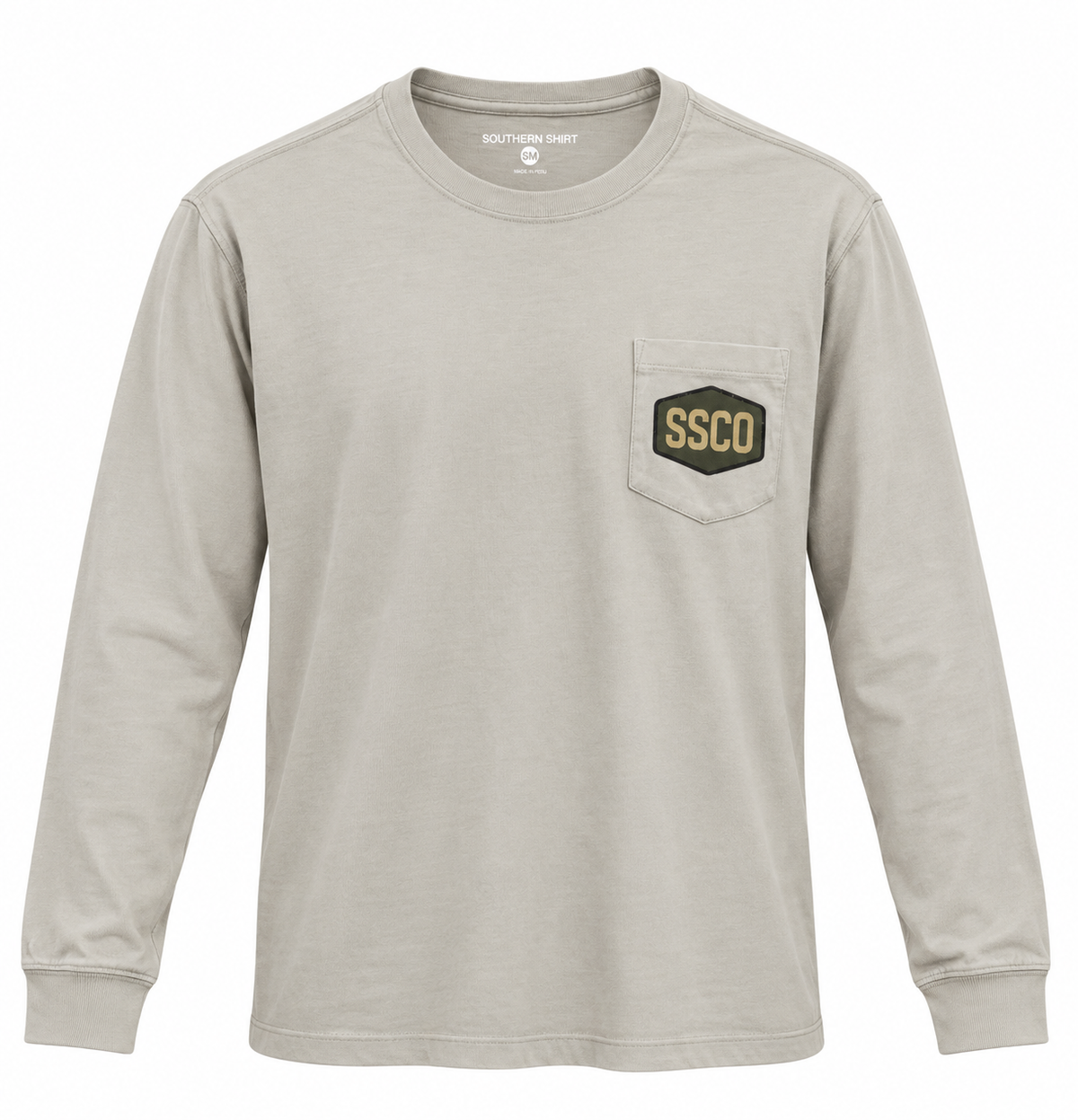 A light beige long-sleeve t-shirt with a chest pocket featuring a hexagonal patch that reads 'SSCO' in gold on a black background. The shirt is displayed flat against a solid white background.