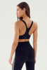 Woman wearing a black sports bra and leggings on a light gray background