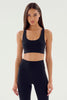 Woman wearing a black sports bra and leggings on a white background