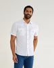 Man standing on white background wearing a white short sleeve button down and jeans