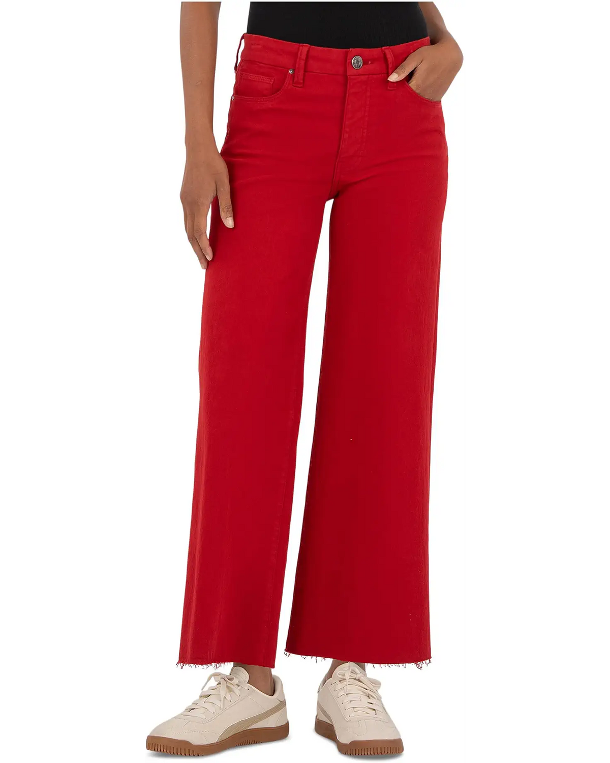 A model wearing bright red wide-leg cropped jeans with a raw frayed hem, paired with cream sneakers, shown from the waist down on a white background.