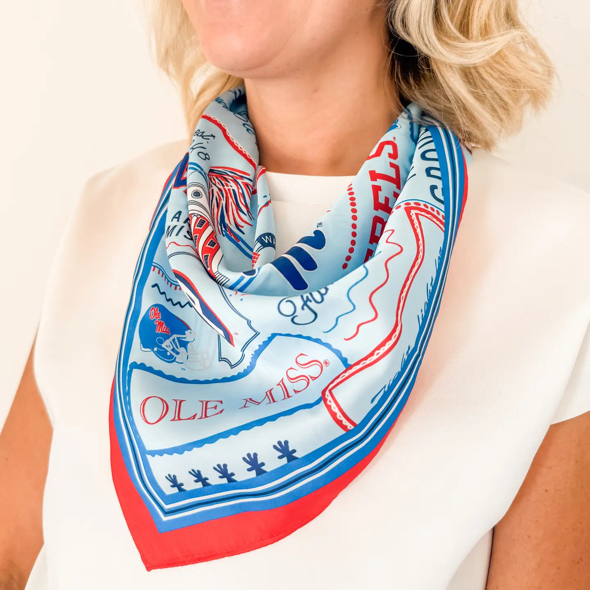 woman modeling a satin scarf around her neck with the words "Ole Miss"