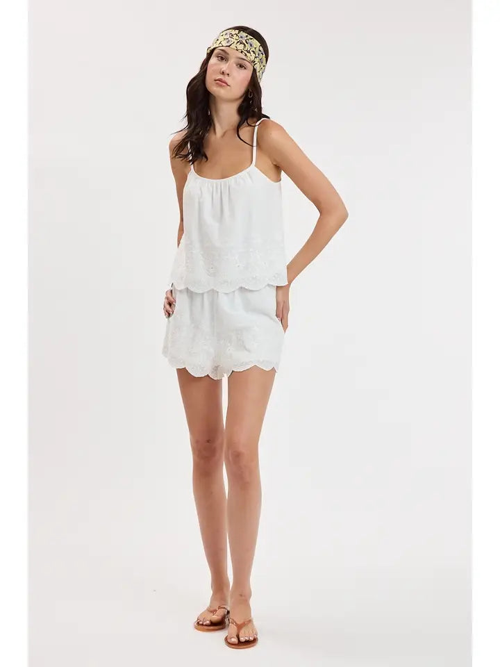 woman standing on white background wearing white eyelet matching set and flip flops