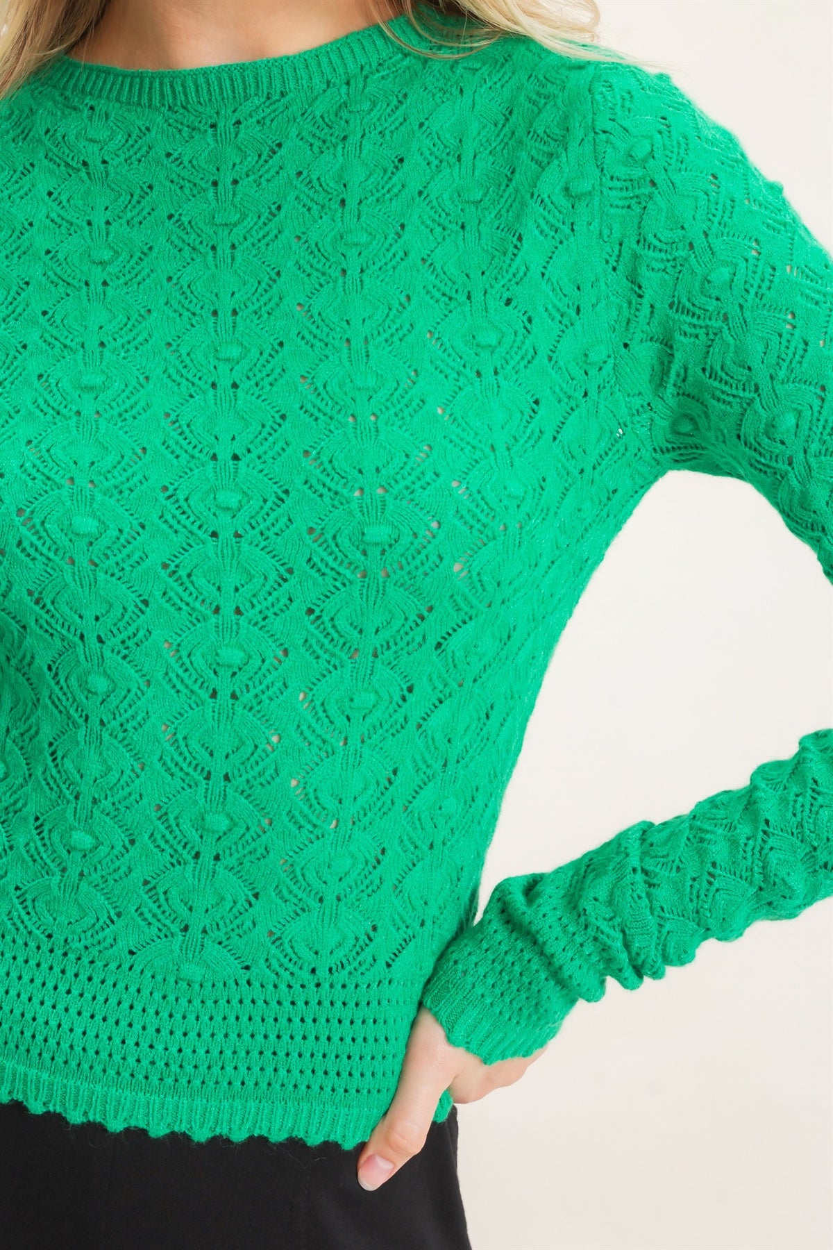 A bright green long-sleeve knit sweater with an intricate textured lace pattern, shown on a model against a plain light background.
