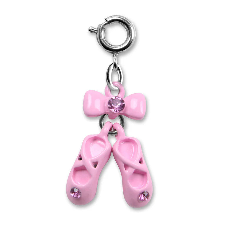 A pink ballet shoe charm featuring two small pink ballet slippers with pink rhinestones, a pink bow with a central pink rhinestone, and a silver-tone clasp at the top.
