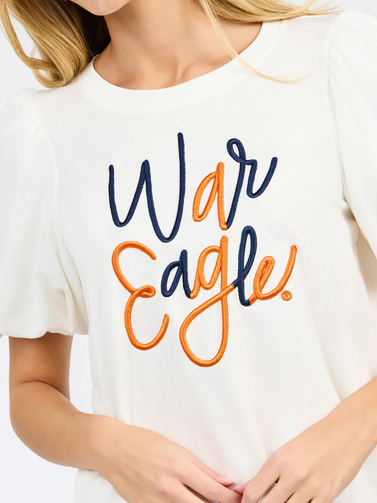 woman modeling a white puff sleeve tee with orange and blue embroidered "war eagle" on the front 