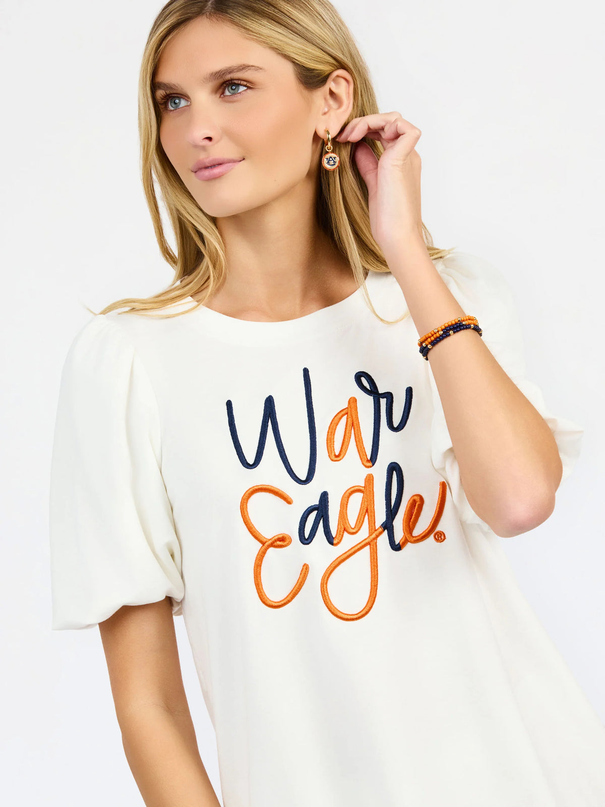 woman modeling a white puff sleeve tee with orange and blue embroidered "war eagle" on the front 