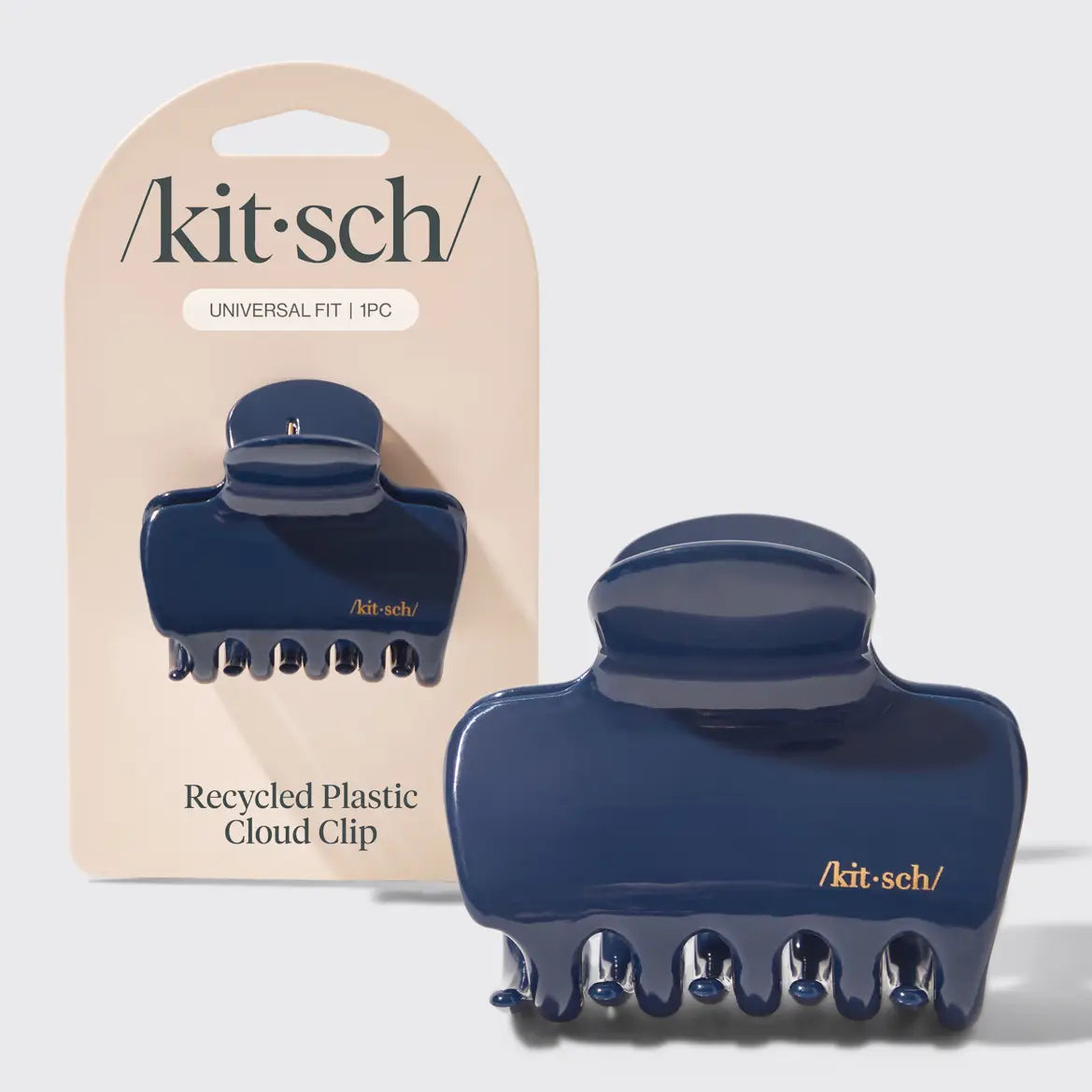 A navy blue recycled plastic cloud clip shown next to its beige retail packaging card. The brand name 'kit-sch' is printed in black on the card, and the clip features gold foil branding.