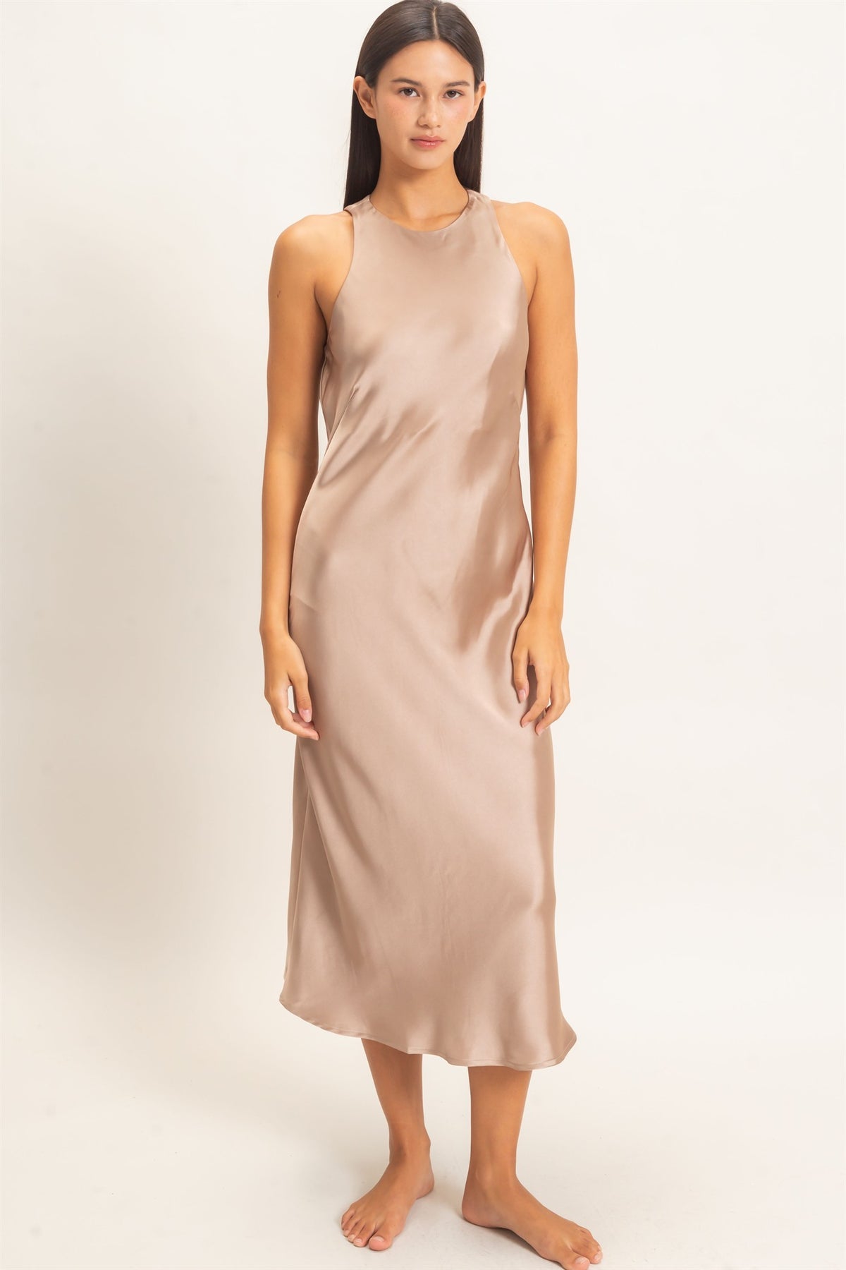 woman standing on white background wearing dark taupe satin dress 