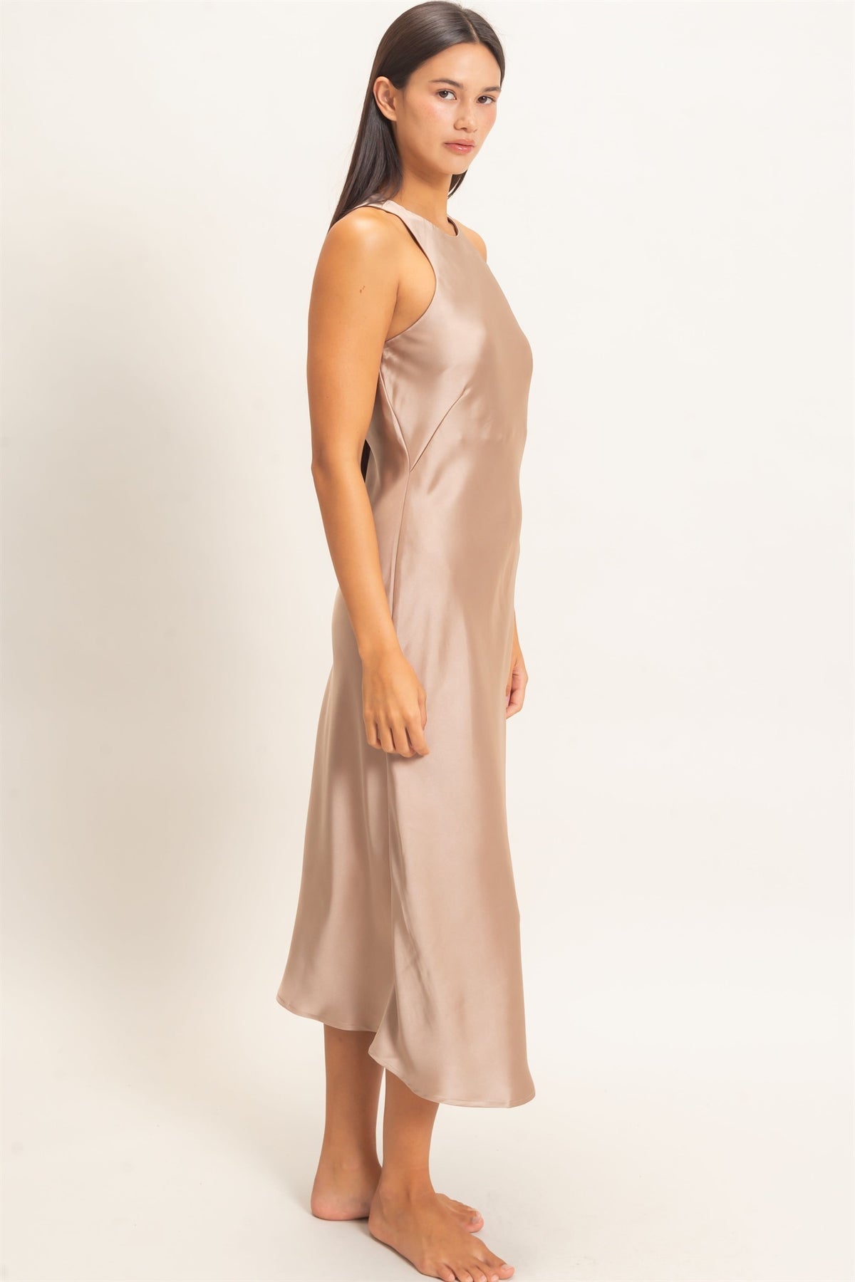 woman standing on white background wearing dark taupe satin dress 