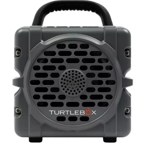 A rugged, portable speaker box by Turtlebox in dark gray, featuring a black carrying handle on top, a large front speaker grille, and the Turtlebox logo printed on the lower front.