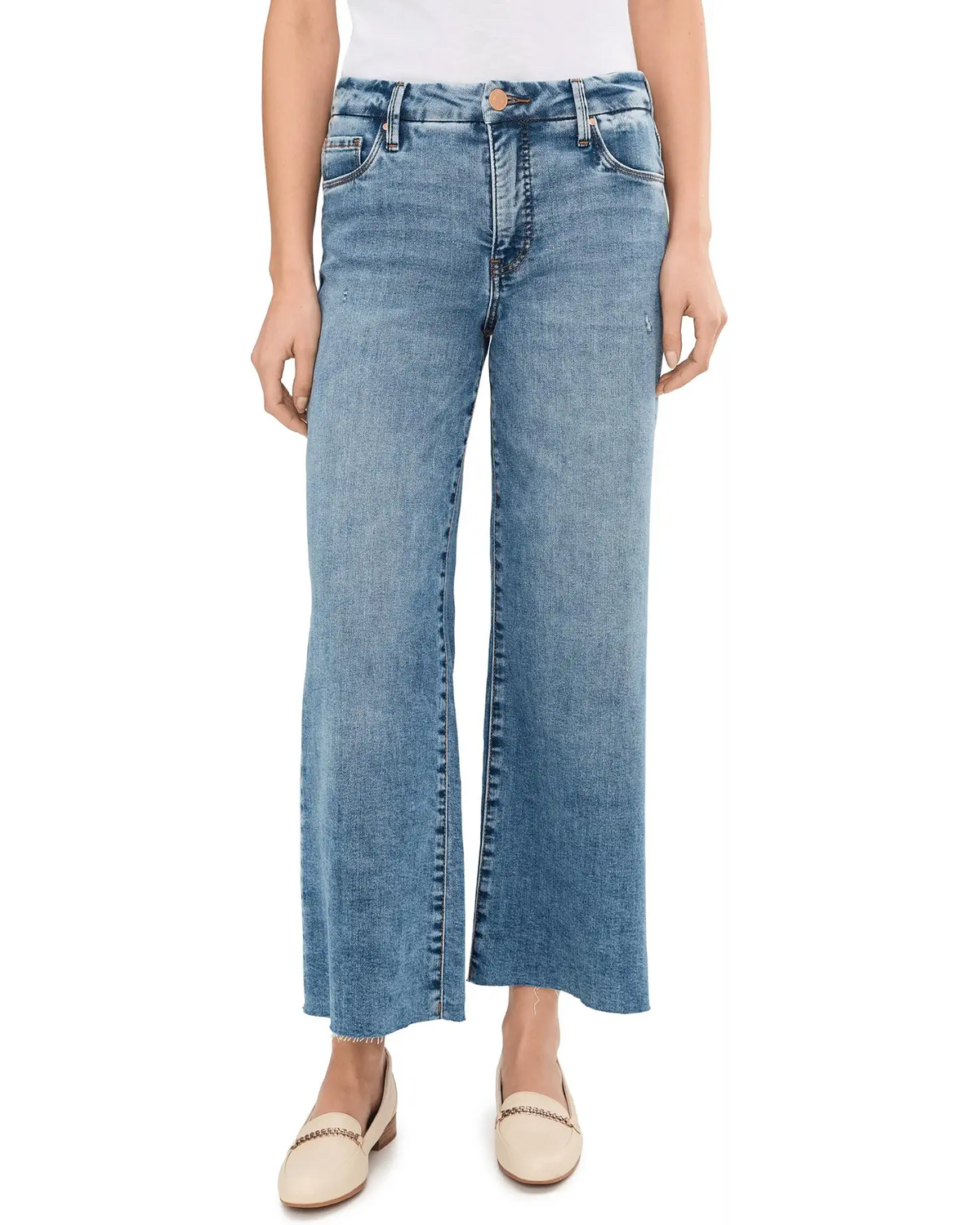 A model wearing a pair of light blue wide-leg cropped jeans with a faded wash, paired with beige flat loafers, shown against a plain white background.