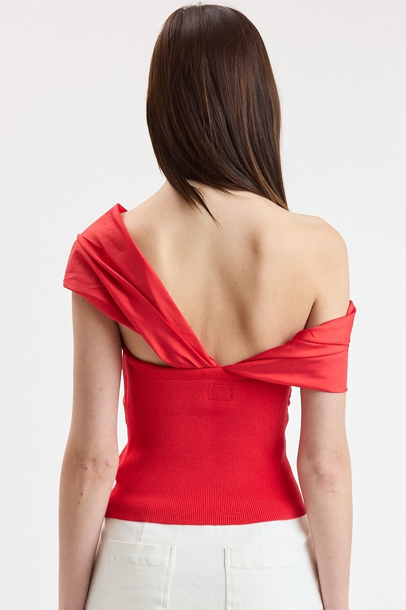 Red off-shoulder top worn by a person on a white background