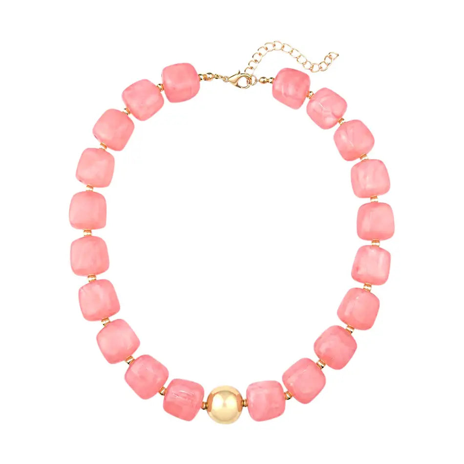 A pink beaded necklace with square-shaped beads and a central gold bead, displayed on a clean white background.
