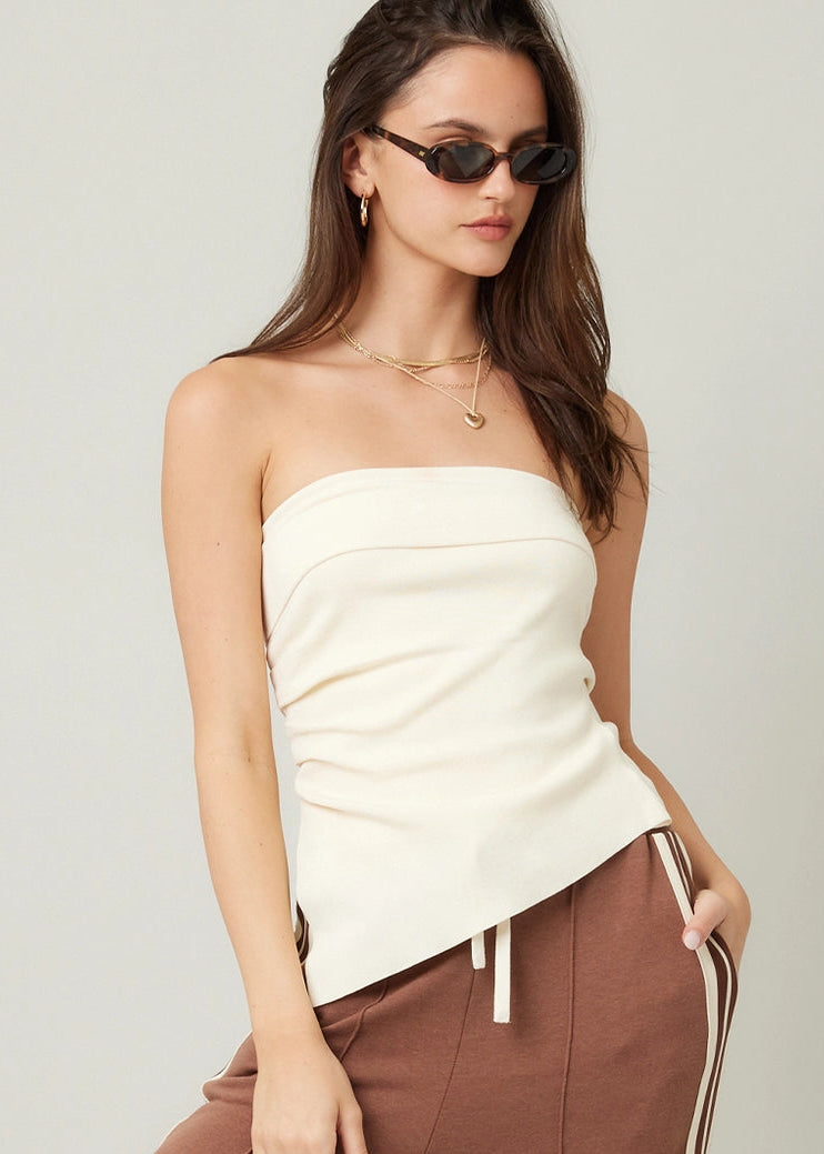 Woman wearing a white strapless top and brown pants with a white background