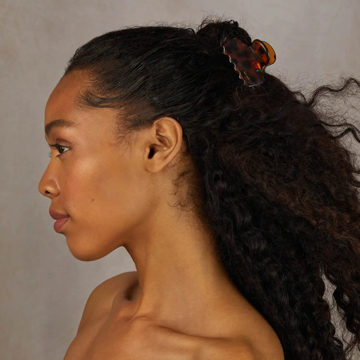 Woman with styled hair in a ponytail against a neutral background