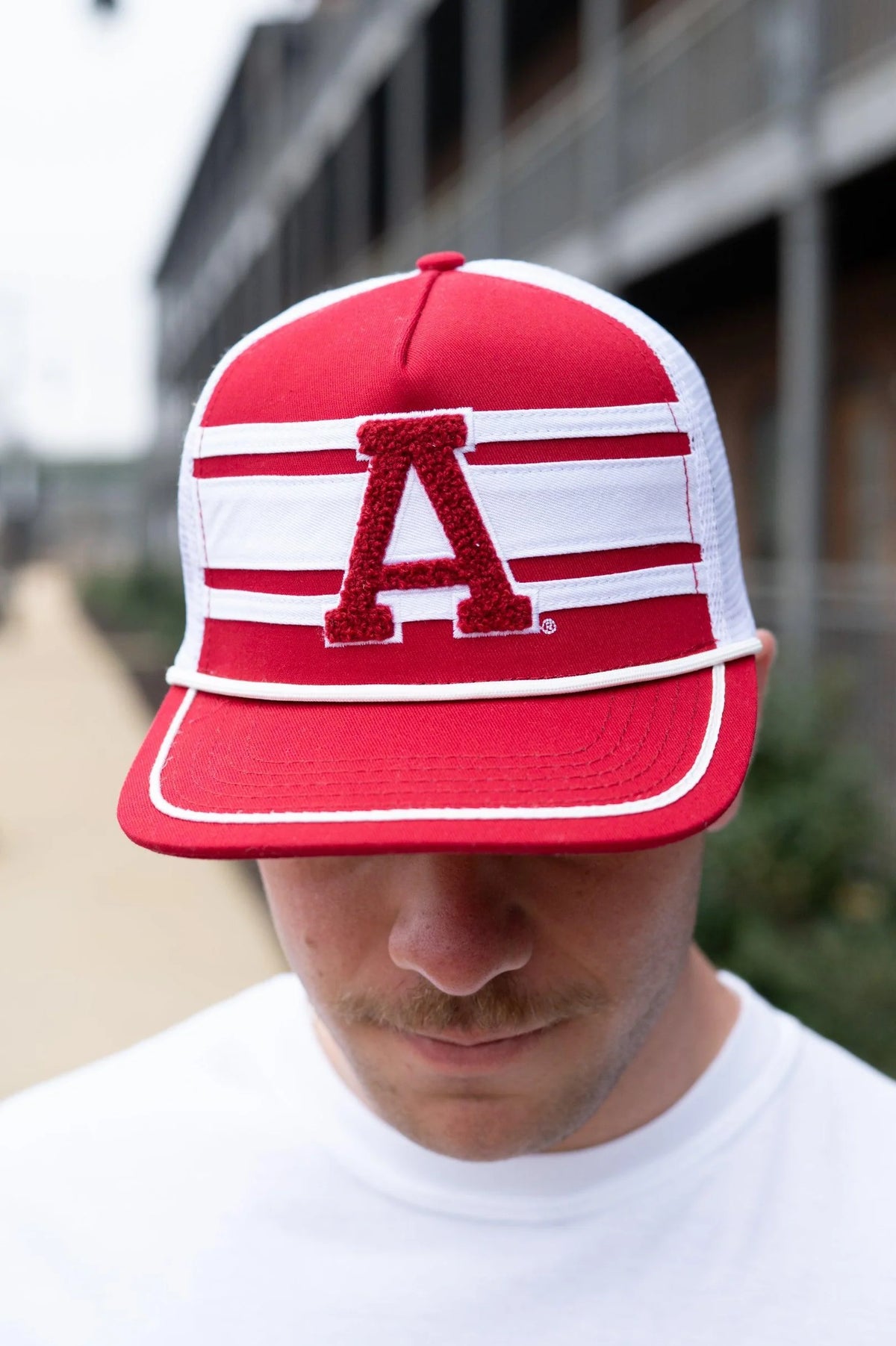 Person wearing a red and white cap with a large 'A' logo, blurred background