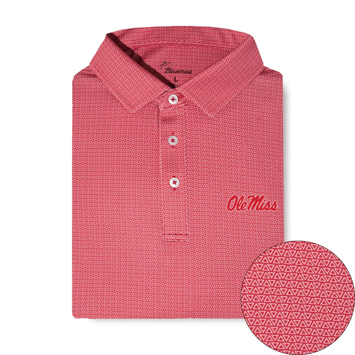 A folded coral pink polo shirt with a textured geometric pattern, featuring a three-button placket, 'Ole Miss' script embroidery on the chest, and a circular inset showing a close-up of the fabric pattern.
