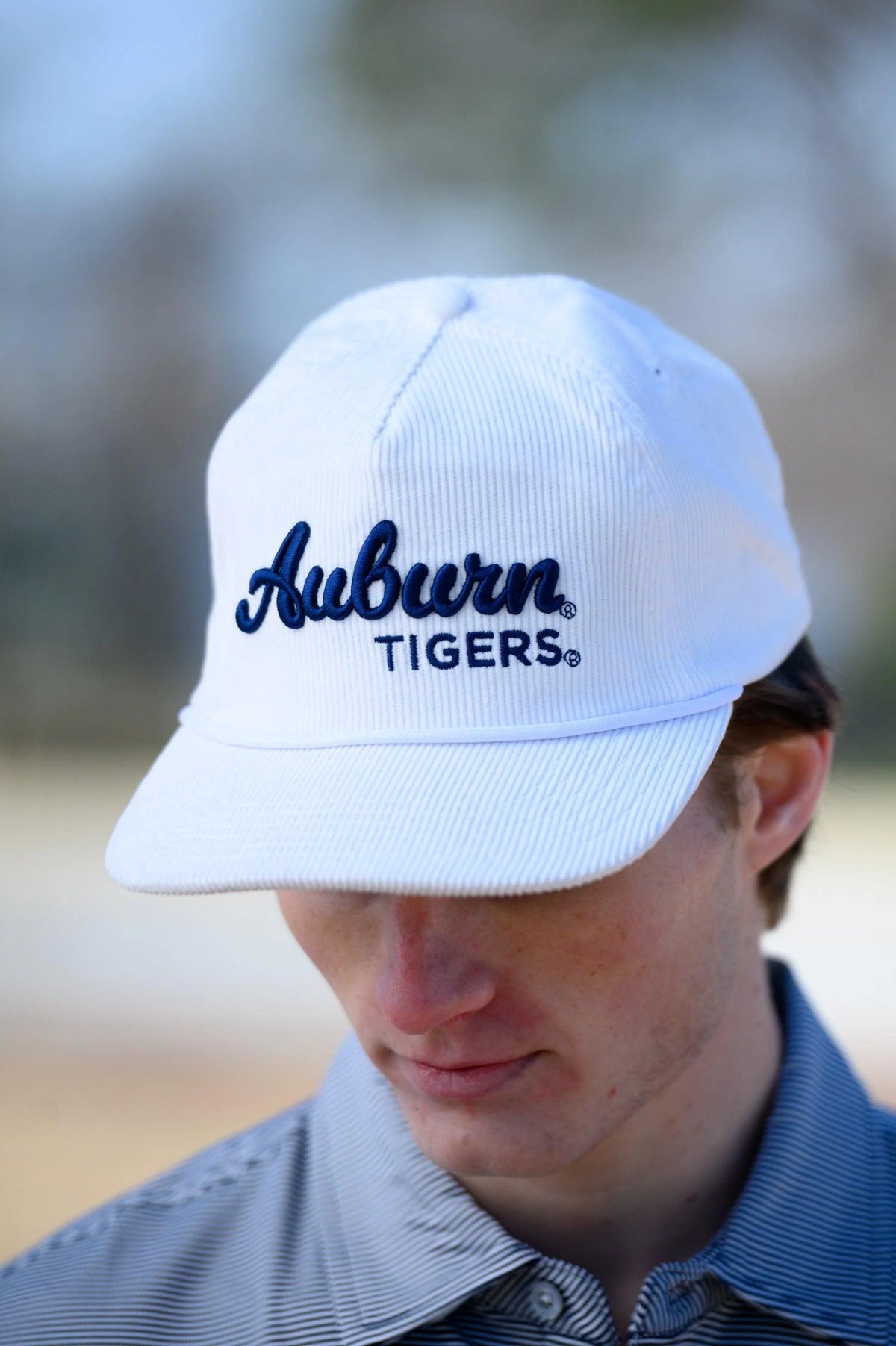 Person wearing a white 'Auburn Tigers' cap outdoors