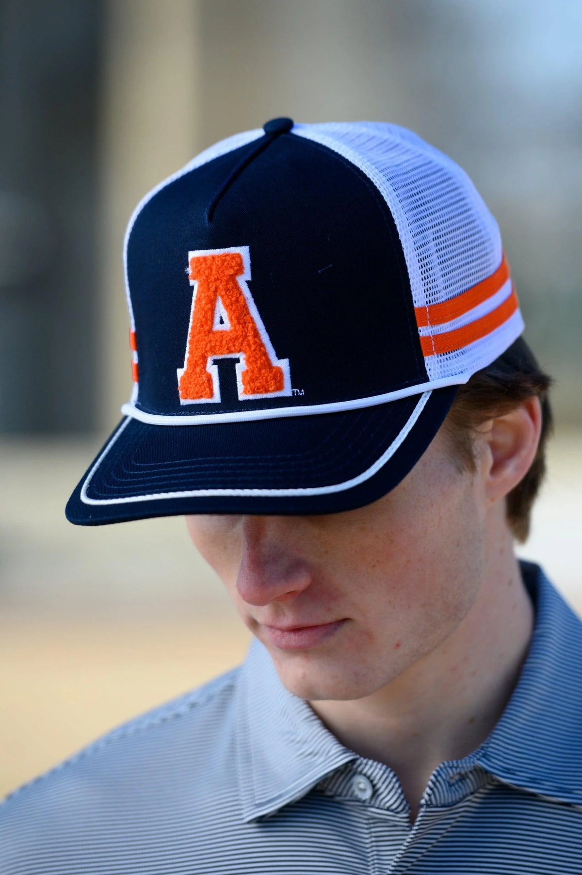 Person wearing a navy and white cap with an orange 'A' logo.