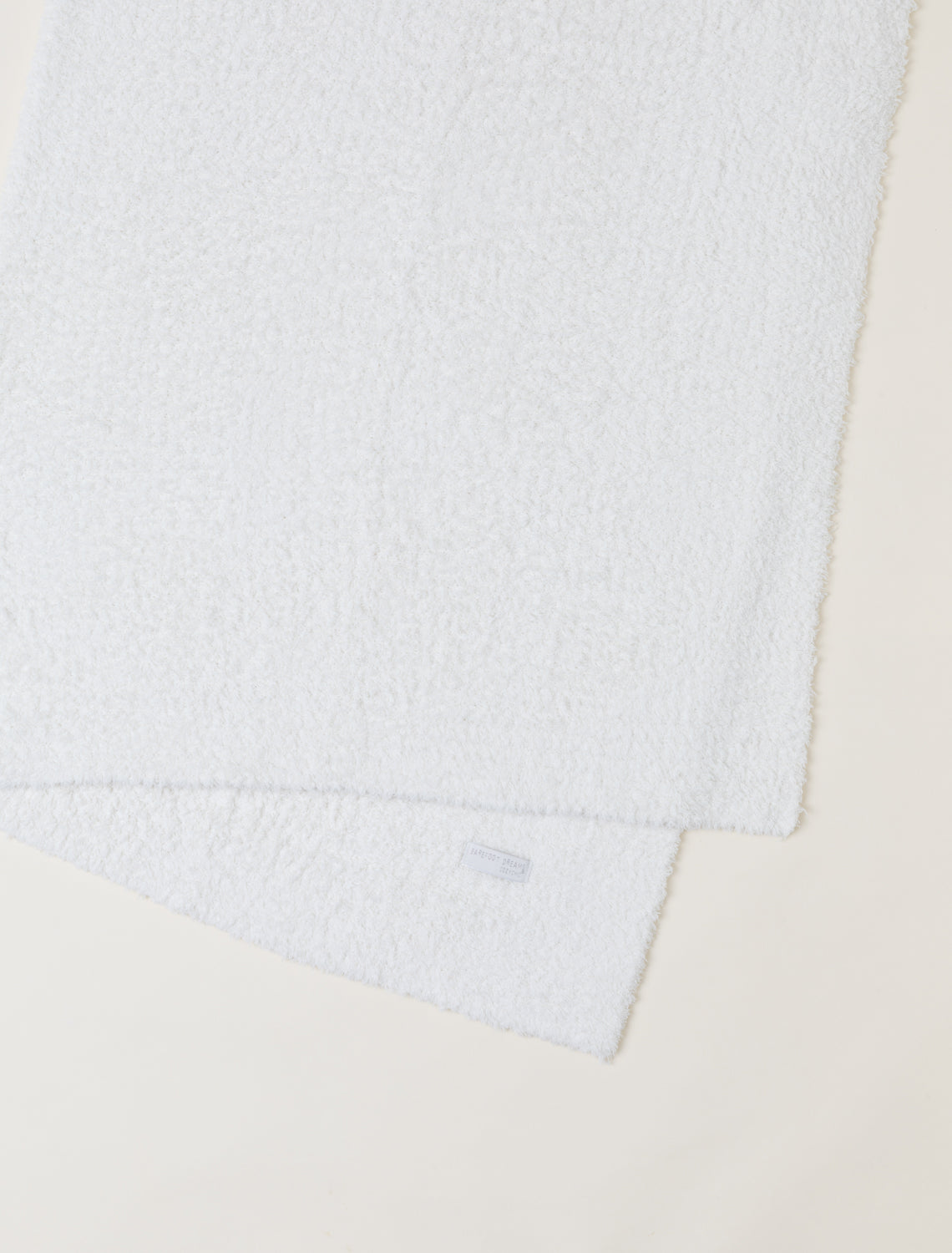 Close-up of a textured white fabric with a brand label on a beige background
