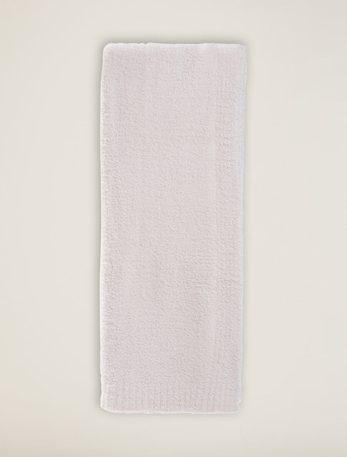 Rectangular white bath mat on a light beige background