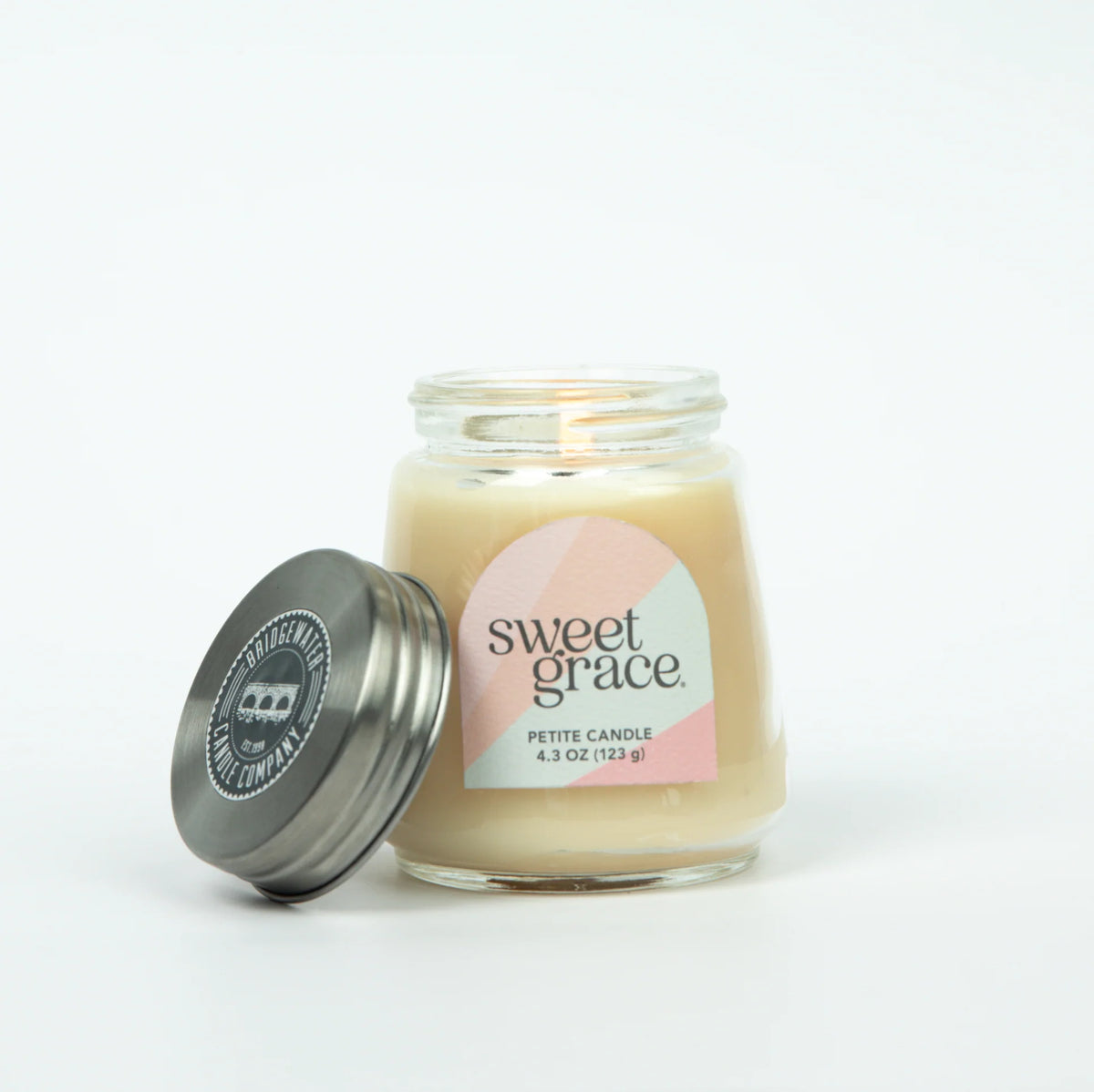 Candle in a glass jar with a metal lid labeled 'sweet grace' on a white background