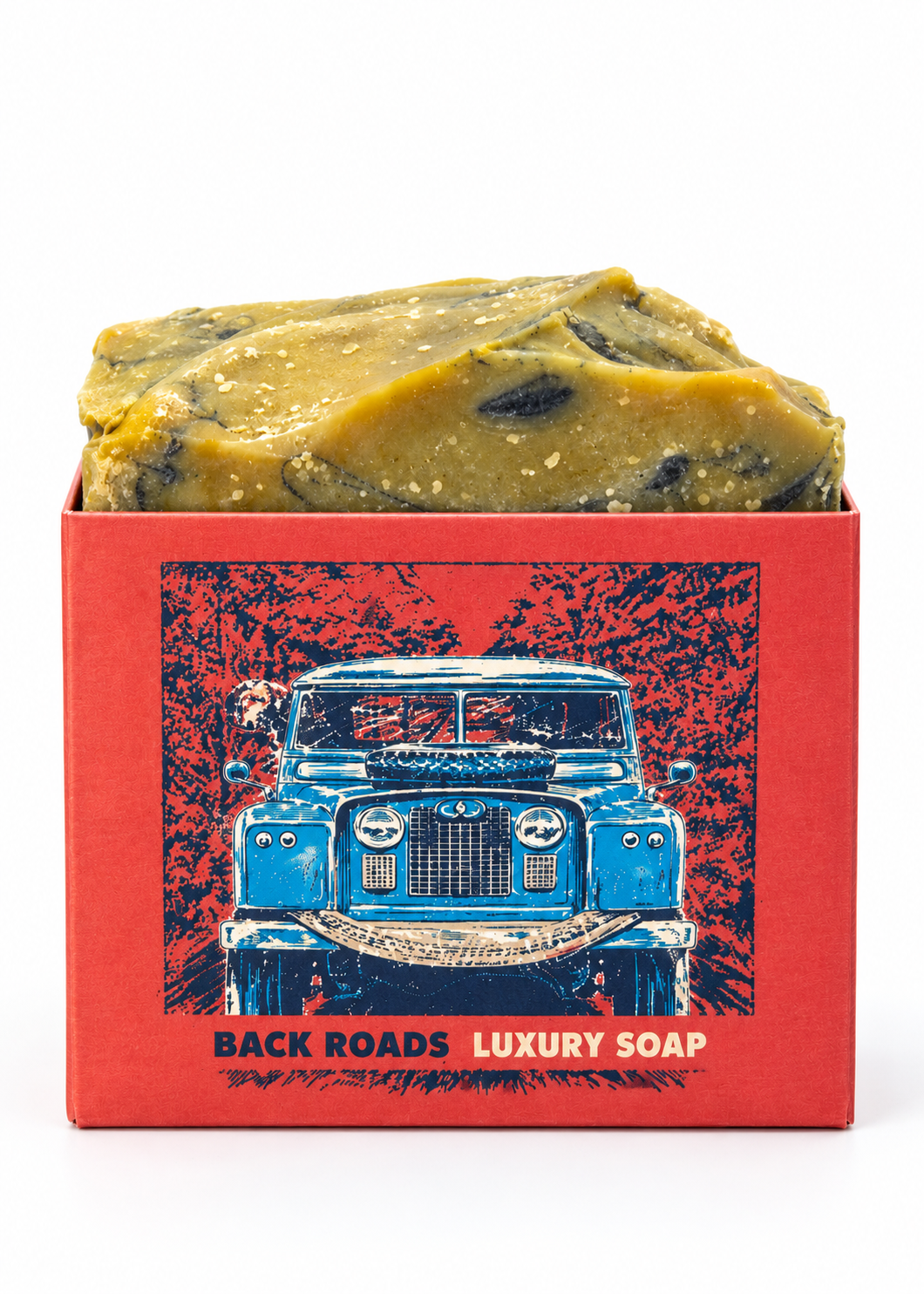A rectangular red soap box filled with a chunky olive-green and yellow bar of soap, featuring a vintage blue truck illustration and the text 'BACKROADS LUXURY SOAP' on a white background.