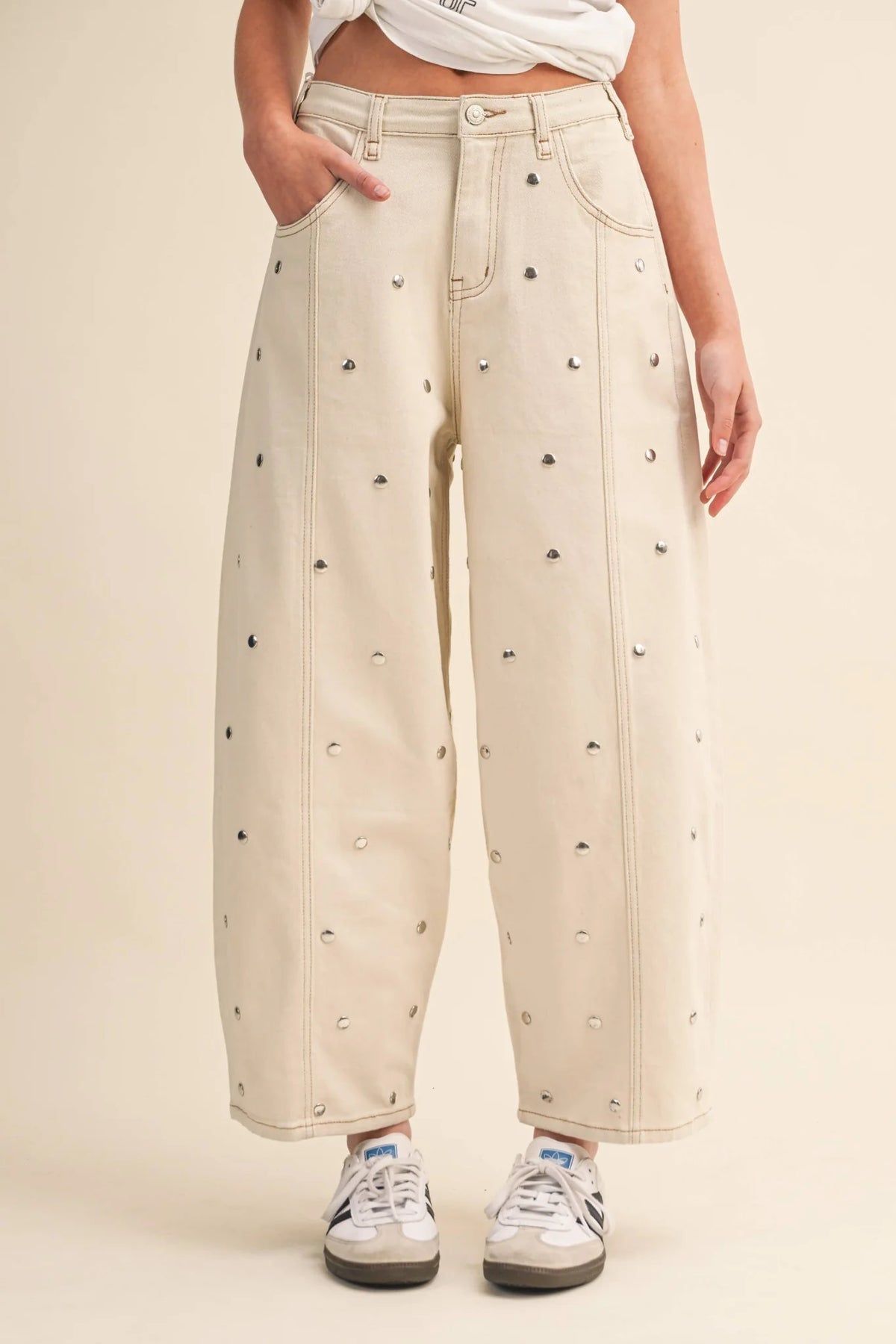 Beige pants with black dot pattern worn by a person on a beige background