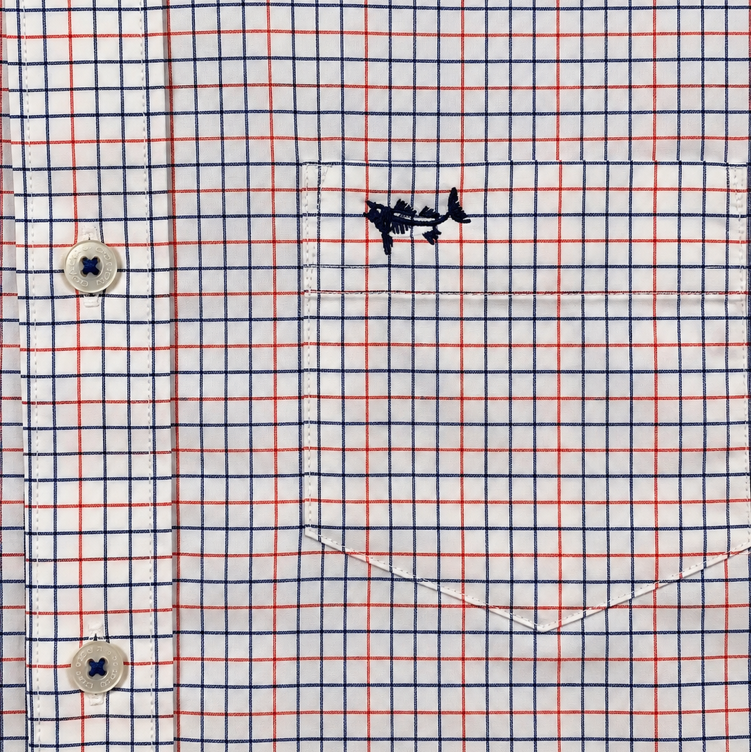 Close-up of a white long-sleeve button-down shirt with a red and navy blue windowpane plaid pattern, featuring a chest pocket with a small embroidered fish logo.