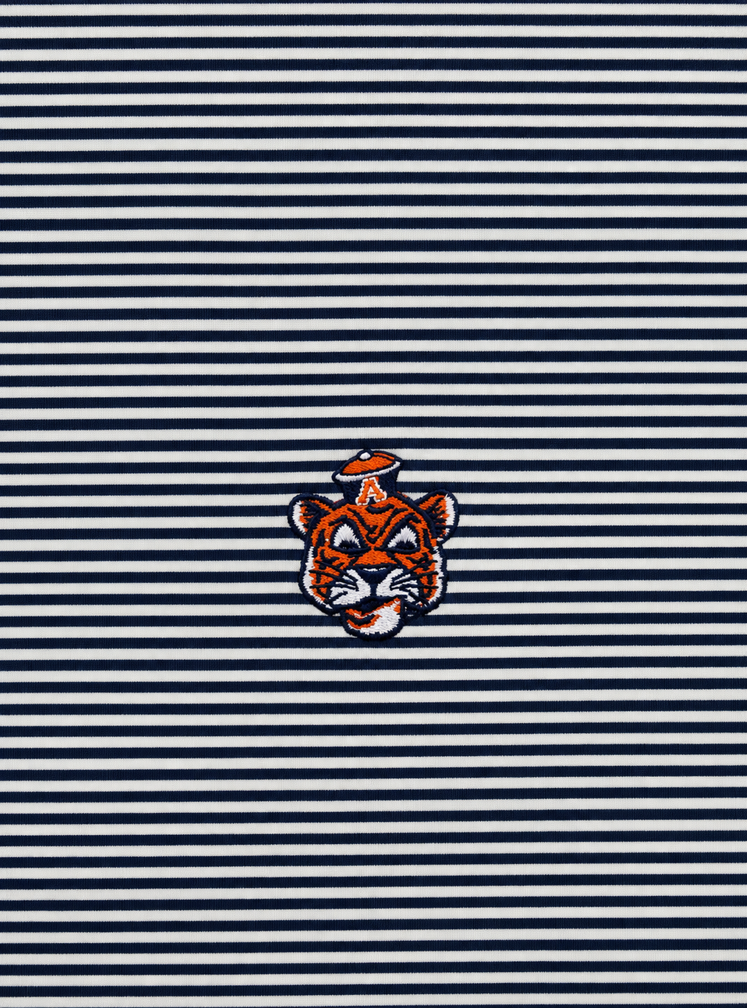 A close-up of a navy and white horizontally striped fabric with a small embroidered tiger mascot patch centered on the stripes.