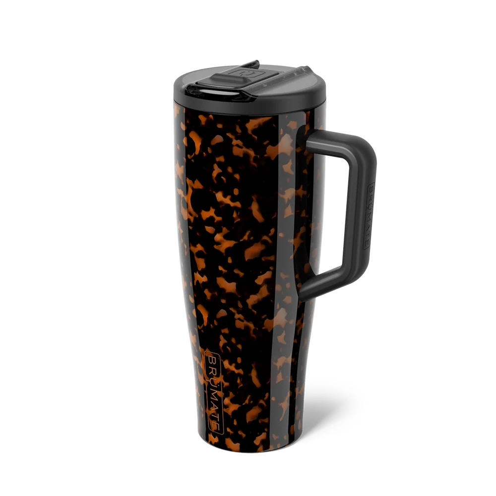 A tall travel tumbler with a black and brown tortoiseshell pattern, featuring a black handle, black lid, and a vertical FRAM logo near the base, shown on a white background.