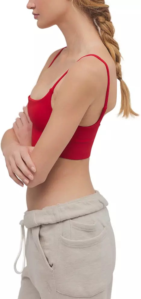A woman shown from the side wearing a bright red spaghetti-strap crop top and light beige drawstring sweatpants against a plain white background.