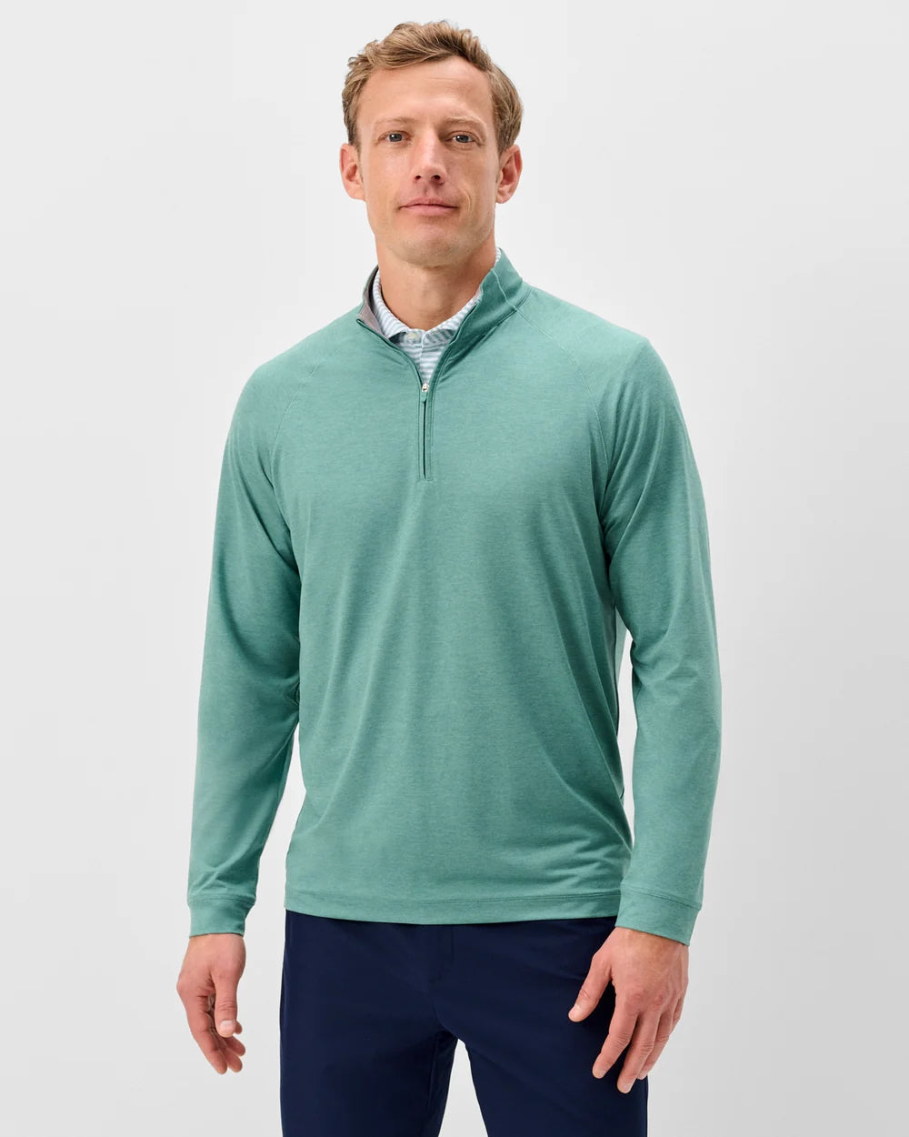 Man wearing a teal long-sleeve shirt with a quarter zip on a light gray background