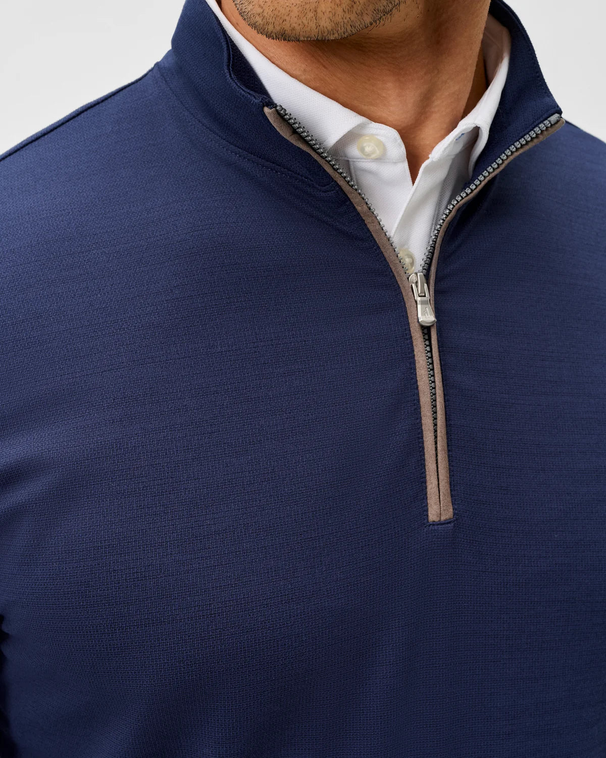 Close of view of the brown front zipper on a navy pullover. 