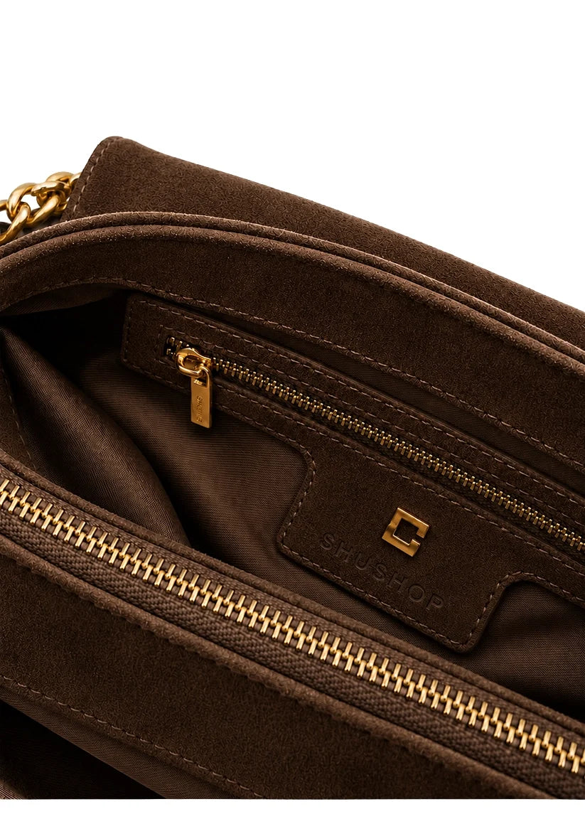 Inner view of the pockets and hardware of a brown purse. 