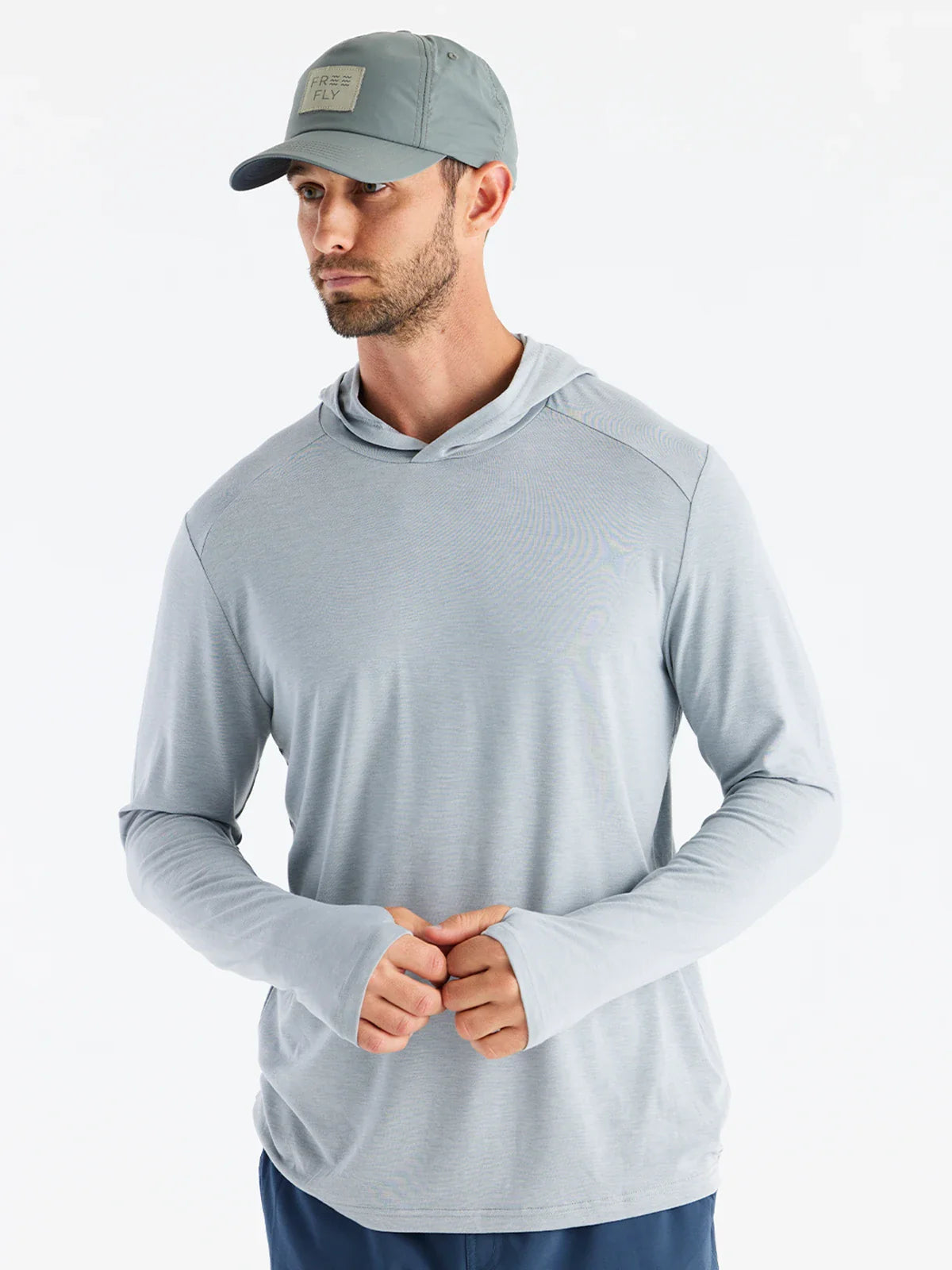 Man wearing a gray long-sleeve athletic shirt and cap on a white background