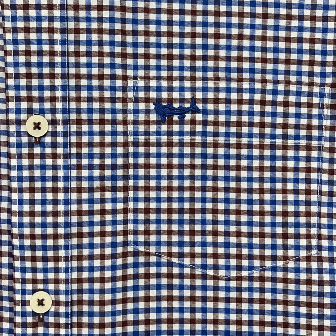 Close-up of a gingham button-down shirt with brown, blue, and white check pattern, featuring a chest pocket with a small blue whale logo and cream-colored buttons.