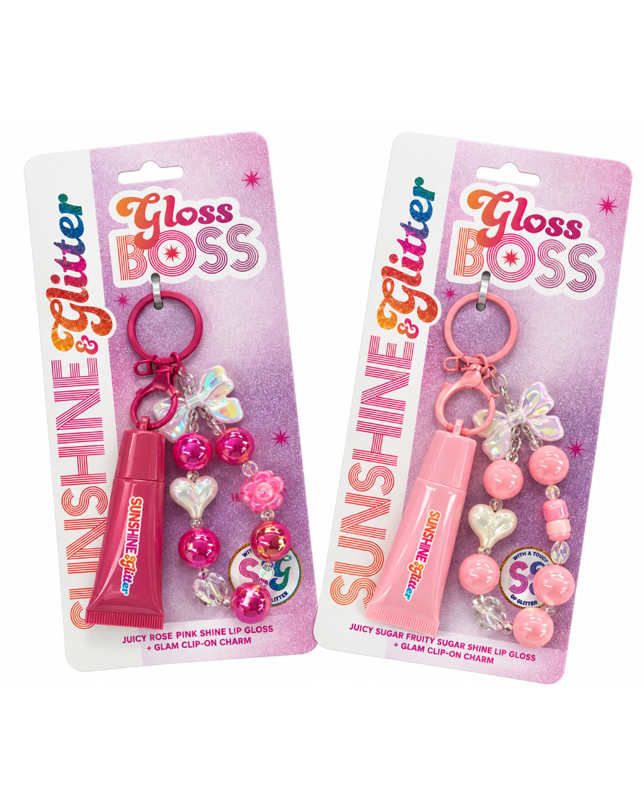Two packaged lip gloss keychains on pink retail cards. One keychain is rose pink with a tube-shaped lip gloss and pink heart charms; the other is light pink with a matching lip gloss and pastel bead/charm details.