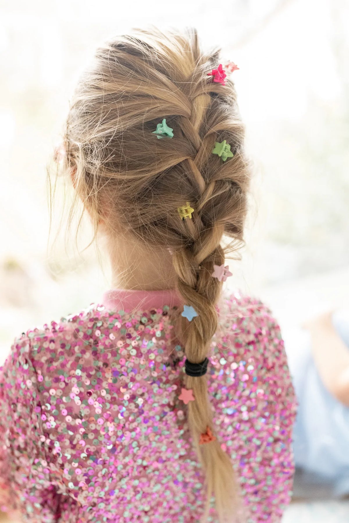 Braided hairstyle decorated with colorful mini star-shaped hair clips.
