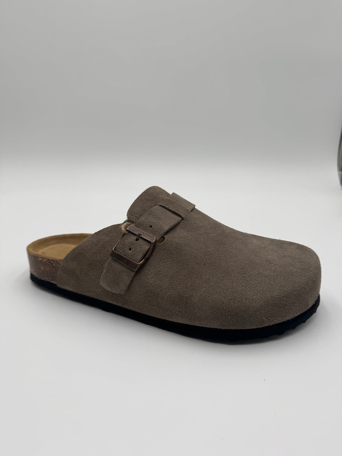 A single taupe-brown suede clog-style mule shoe with a double-buckle strap and a black sole, photographed on a light gray studio background.